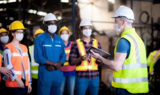 Manager Assigns Job Training to Technicians with Safety Helmets and Masks