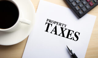 Text Property Taxes is on the white paper with coffee, calculator and ball pen aside.