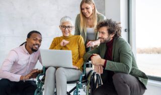 Women discusses business items with team in front of a laptop
